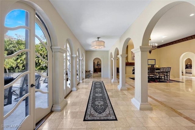 foyer with decorative columns, arched walkways, baseboards, and an inviting chandelier