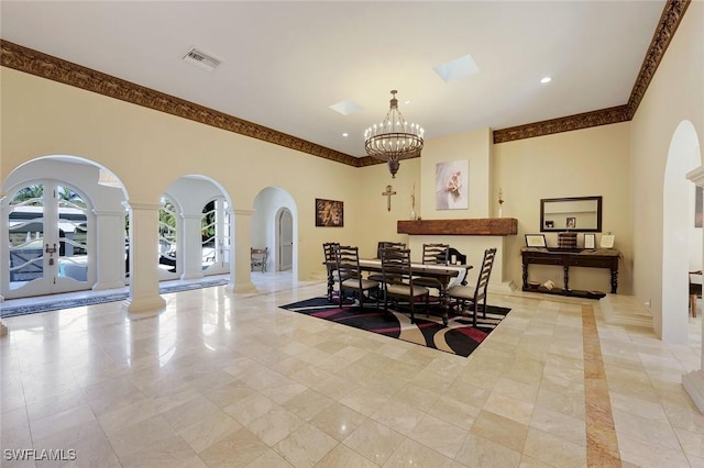 dining area with visible vents, a high ceiling, decorative columns, arched walkways, and a chandelier