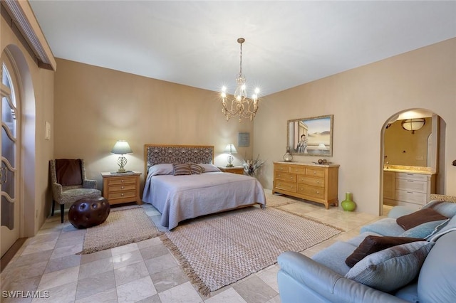 bedroom with arched walkways, a notable chandelier, and ensuite bath