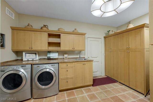 laundry room with light tile patterned floors, visible vents, cabinet space, separate washer and dryer, and a sink