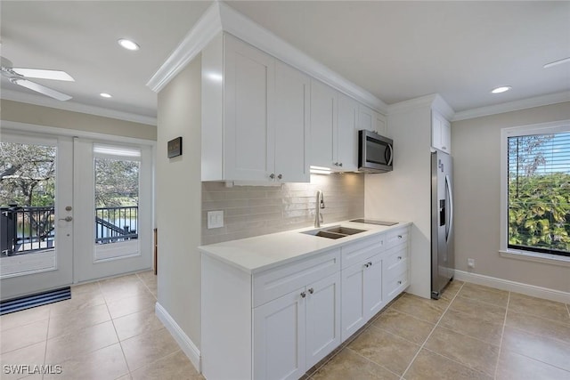 kitchen with backsplash, crown molding, light countertops, stainless steel appliances, and a sink