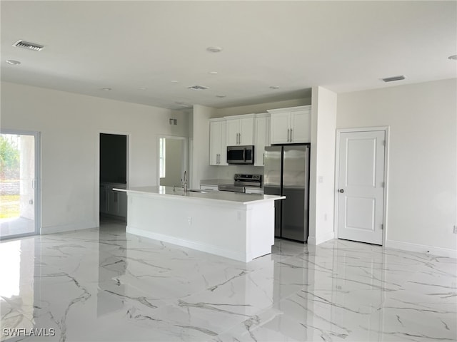 kitchen featuring visible vents, marble finish floor, a kitchen island with sink, appliances with stainless steel finishes, and white cabinets