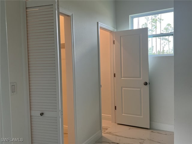 hall with baseboards and marble finish floor