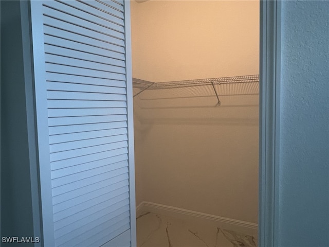 walk in closet with marble finish floor