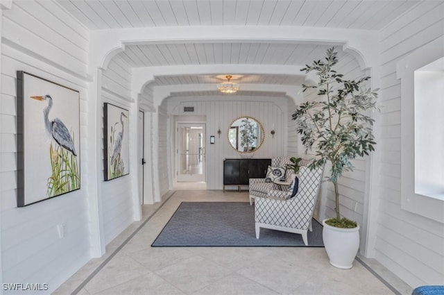 hall featuring beamed ceiling and wood walls