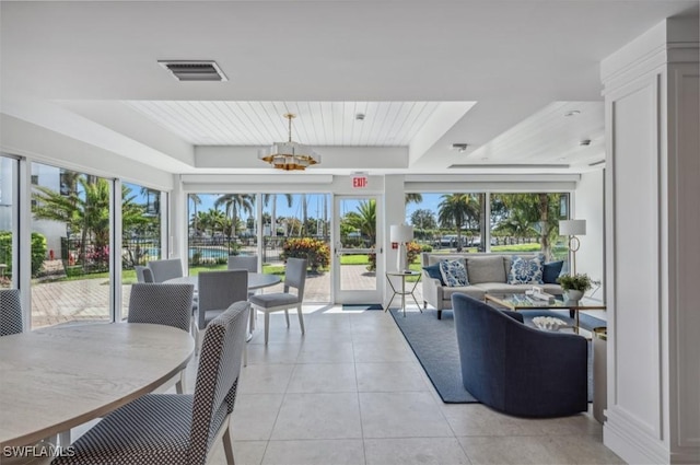 sunroom / solarium featuring a chandelier, visible vents, a healthy amount of sunlight, and a raised ceiling