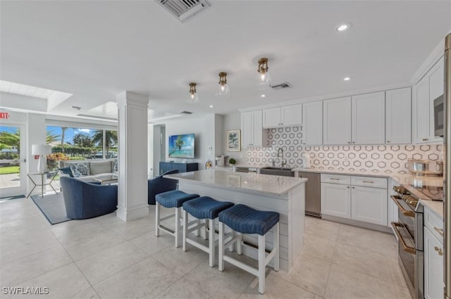 kitchen with tasteful backsplash, visible vents, open floor plan, double oven range, and a sink