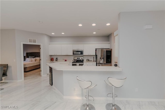 kitchen with visible vents, stainless steel appliances, light countertops, white cabinetry, and a kitchen breakfast bar