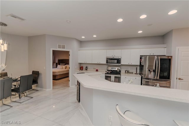 kitchen with visible vents, pendant lighting, white cabinetry, appliances with stainless steel finishes, and light countertops