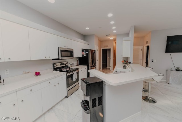 kitchen featuring a breakfast bar, light countertops, white cabinetry, and appliances with stainless steel finishes