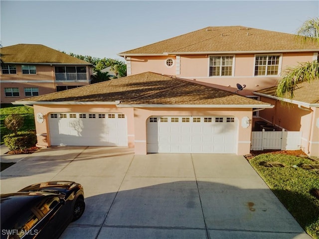 view of front facade with stucco siding, driveway, and fence