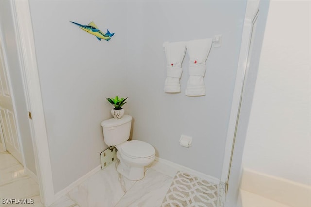 bathroom featuring toilet, baseboards, and marble finish floor