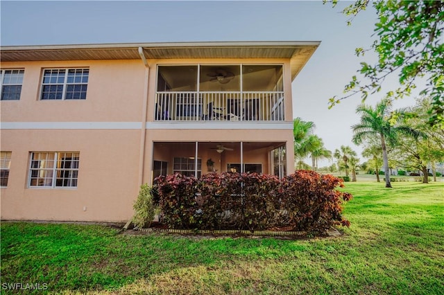 back of property featuring stucco siding, a lawn, ceiling fan, and a balcony