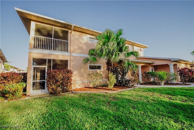 rear view of property featuring a yard and stucco siding