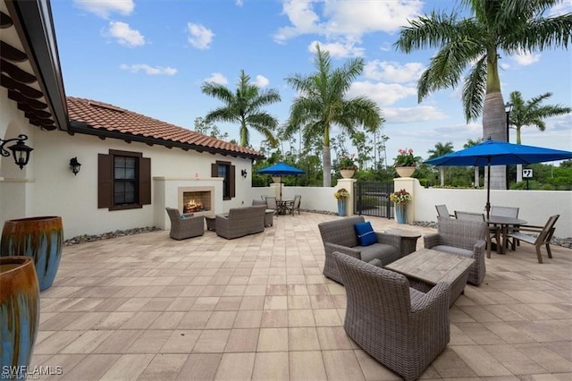 view of patio / terrace featuring fence, a gate, an outdoor living space with a fireplace, and outdoor dining area