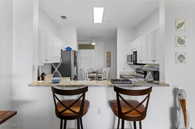 kitchen featuring a peninsula, white cabinets, visible vents, and appliances with stainless steel finishes