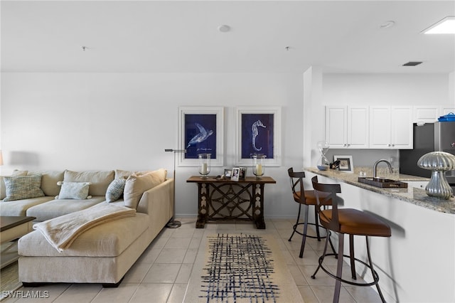 living area with light tile patterned floors, visible vents, and baseboards