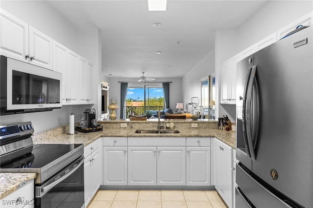 kitchen featuring light tile patterned floors, appliances with stainless steel finishes, white cabinetry, and a sink