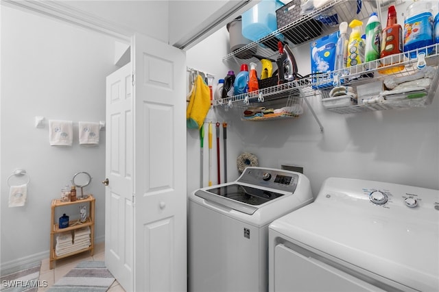 clothes washing area with light tile patterned floors, baseboards, separate washer and dryer, and laundry area