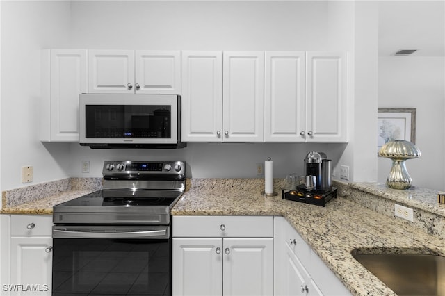 kitchen with electric range, visible vents, light stone counters, white cabinetry, and white microwave