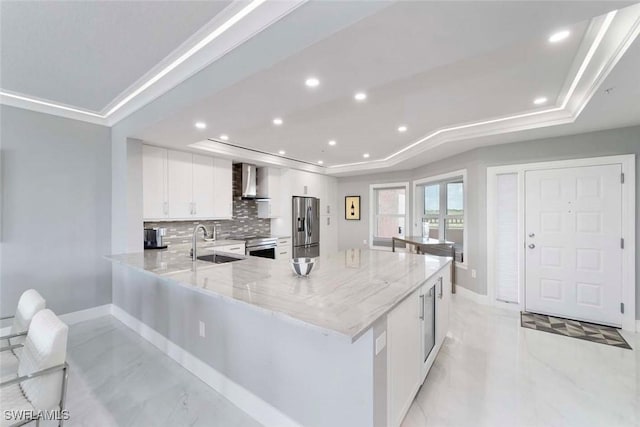 kitchen featuring a sink, a tray ceiling, light stone countertops, and stainless steel appliances