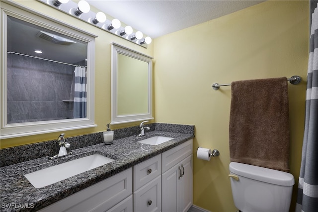 bathroom with a sink, toilet, and double vanity