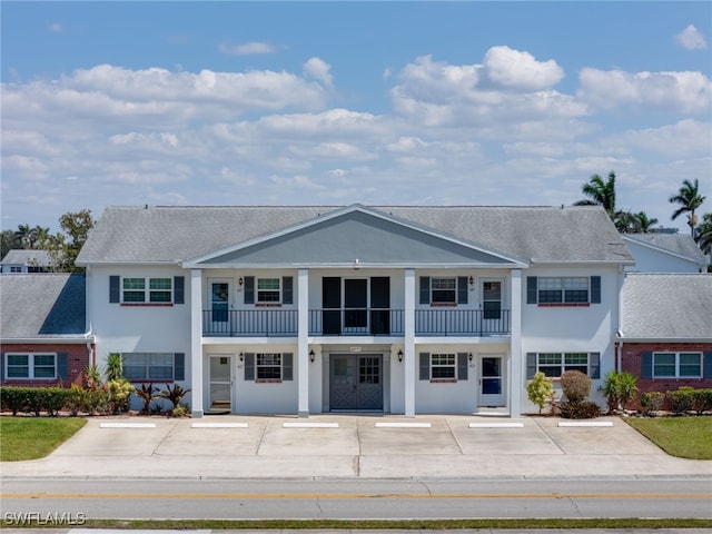 greek revival inspired property with stucco siding and uncovered parking