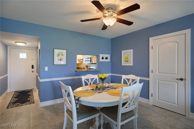 dining area featuring baseboards, a ceiling fan, and tile patterned flooring