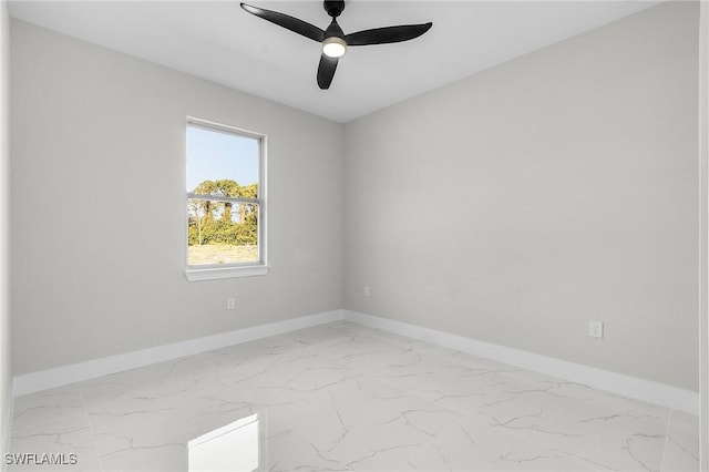 empty room featuring marble finish floor, a ceiling fan, and baseboards