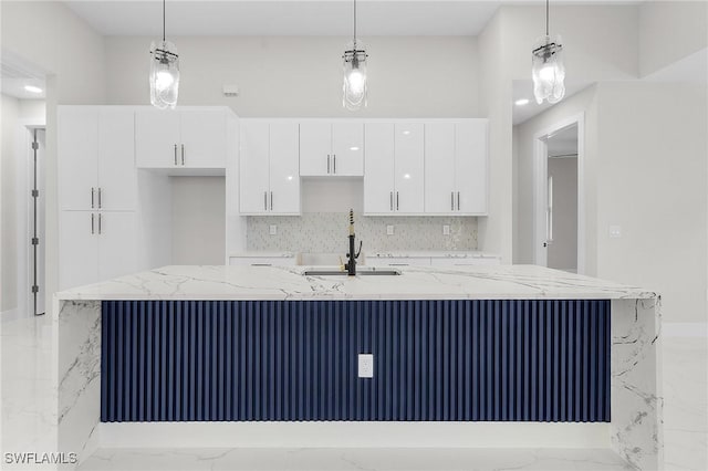 kitchen featuring a large island, white cabinets, decorative light fixtures, and marble finish floor