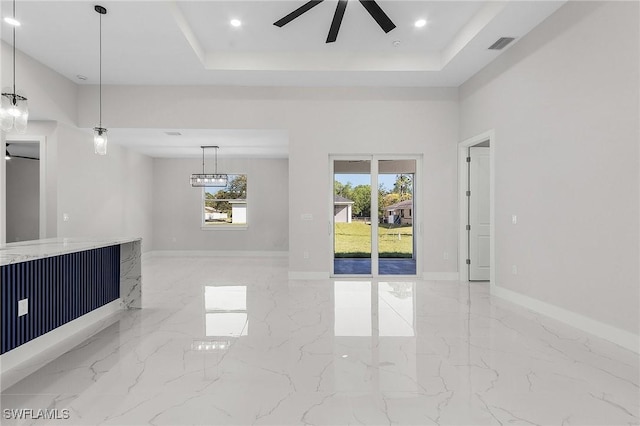 empty room featuring a raised ceiling, a ceiling fan, visible vents, and marble finish floor