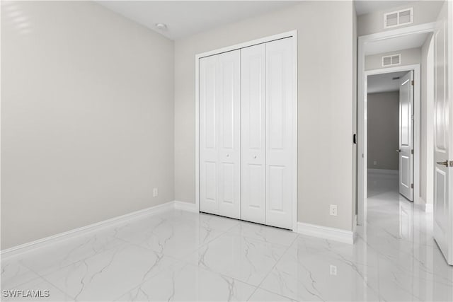 unfurnished bedroom with a closet, baseboards, visible vents, and marble finish floor