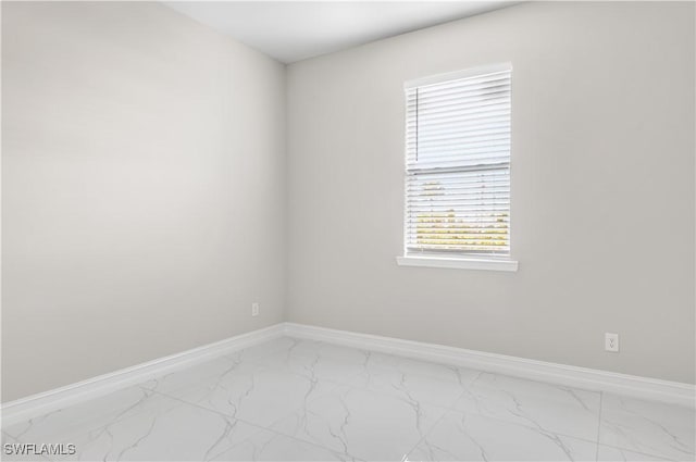 unfurnished room featuring baseboards and marble finish floor