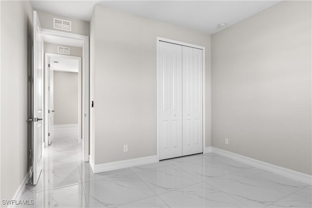 unfurnished bedroom featuring a closet, visible vents, marble finish floor, and baseboards