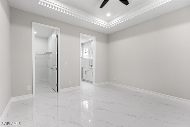 bedroom featuring a raised ceiling, marble finish floor, ornamental molding, baseboards, and a spacious closet