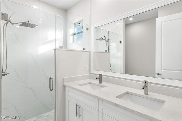 bathroom with a marble finish shower, double vanity, and a sink