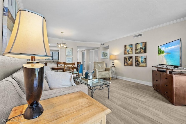 living room featuring visible vents, crown molding, baseboards, an inviting chandelier, and light wood-style floors