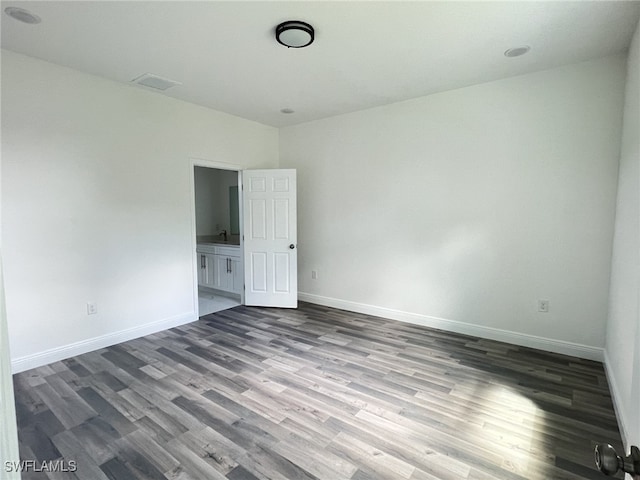 empty room featuring visible vents, baseboards, and dark wood-style flooring