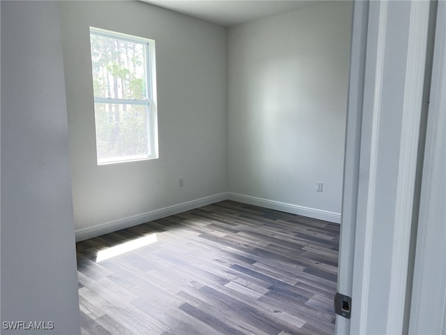 spare room with baseboards and dark wood-style flooring