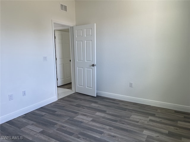 unfurnished room with visible vents, dark wood-type flooring, and baseboards