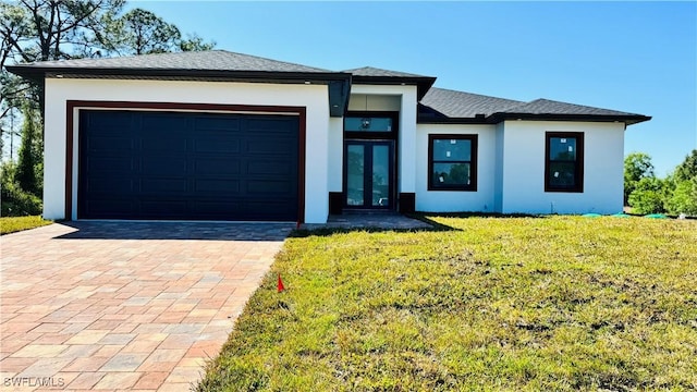 prairie-style house featuring a front yard, stucco siding, french doors, a garage, and decorative driveway