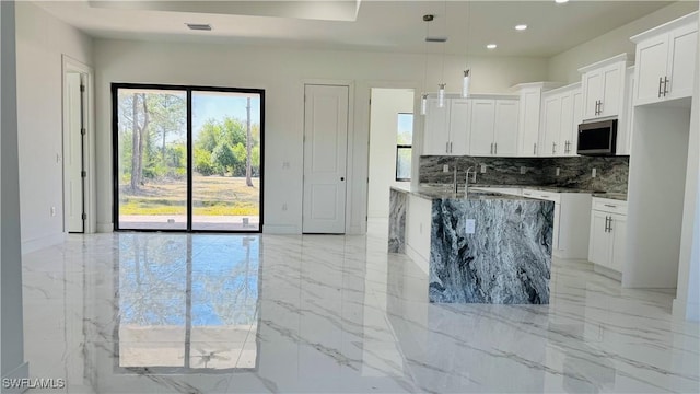 kitchen with visible vents, marble finish floor, stainless steel microwave, backsplash, and stone counters