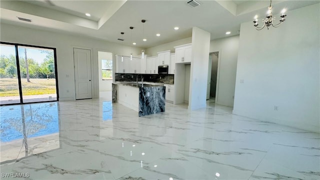 kitchen featuring stainless steel microwave, open floor plan, recessed lighting, an inviting chandelier, and white cabinets