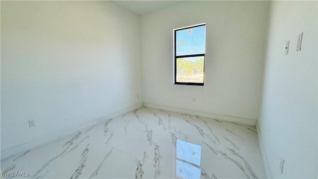 unfurnished room featuring baseboards and marble finish floor