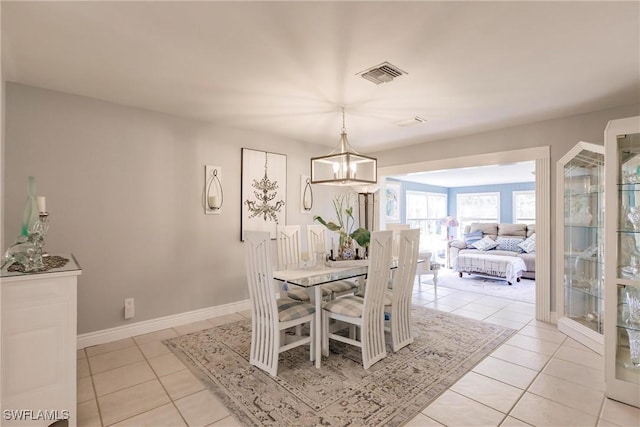 dining area featuring light tile patterned floors, visible vents, baseboards, and an inviting chandelier