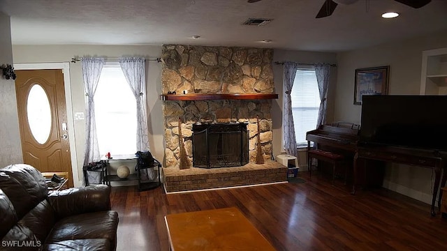 living room featuring visible vents, wood finished floors, ceiling fan, and a fireplace