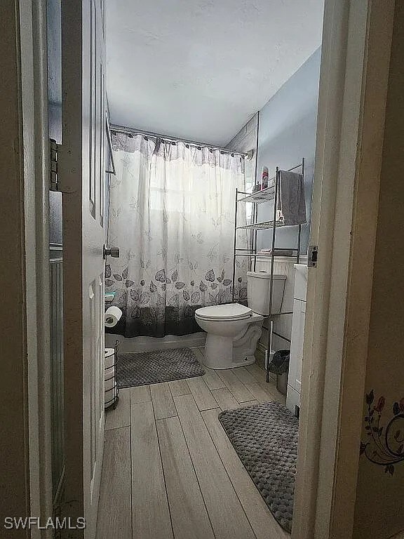 1280 Mcneill Rd, North Fort Myers, FL 33903 - full bathroom with shower / bathtub combination with curtain, toilet, and wood finished floors