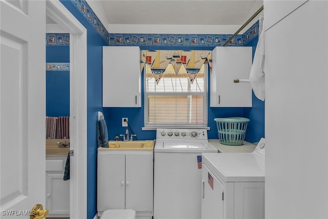 washroom featuring a sink, cabinet space, a textured ceiling, and separate washer and dryer