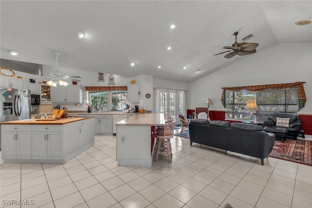 kitchen featuring visible vents, a ceiling fan, open floor plan, and wood counters