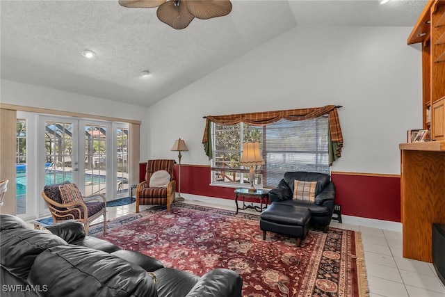 living room with wainscoting, french doors, a textured ceiling, and vaulted ceiling